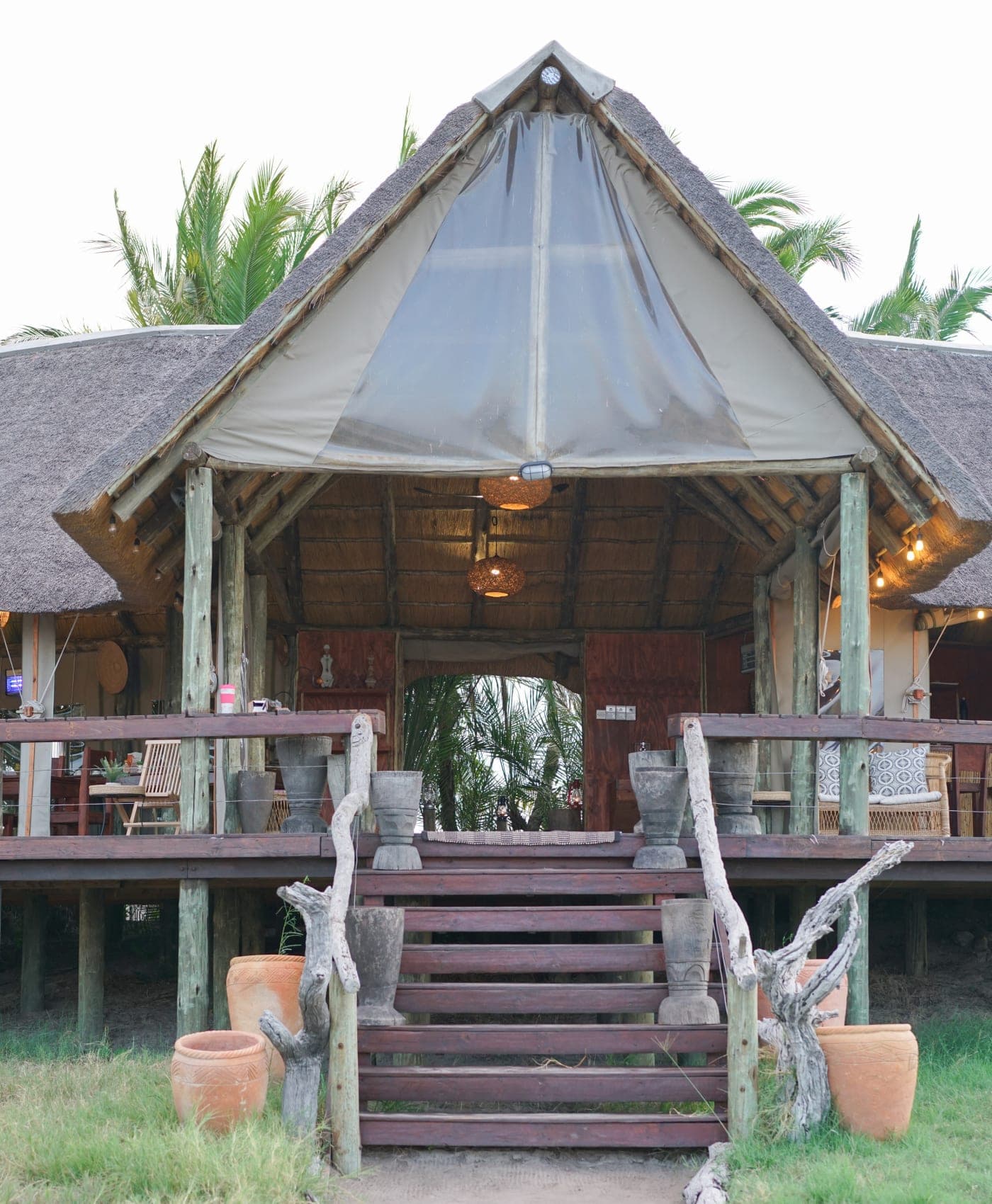 The main area at Munga Plains, wooden steps up to a thatched deck lit by lanterns